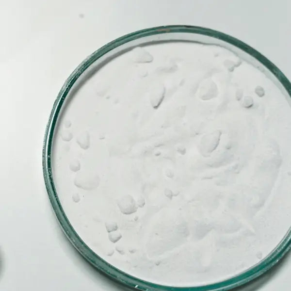 A glass petri dish filled with fine white zinc oxide powder on a white surface