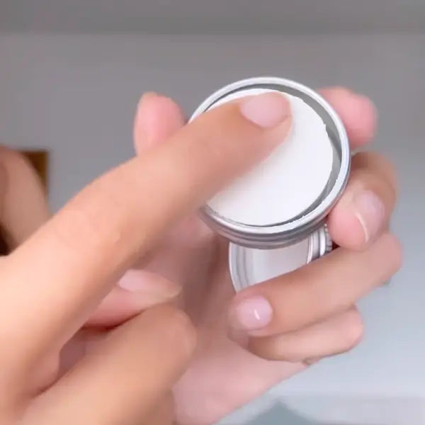 Hands opening a white deodorant container with a silver lid, revealing the cream inside