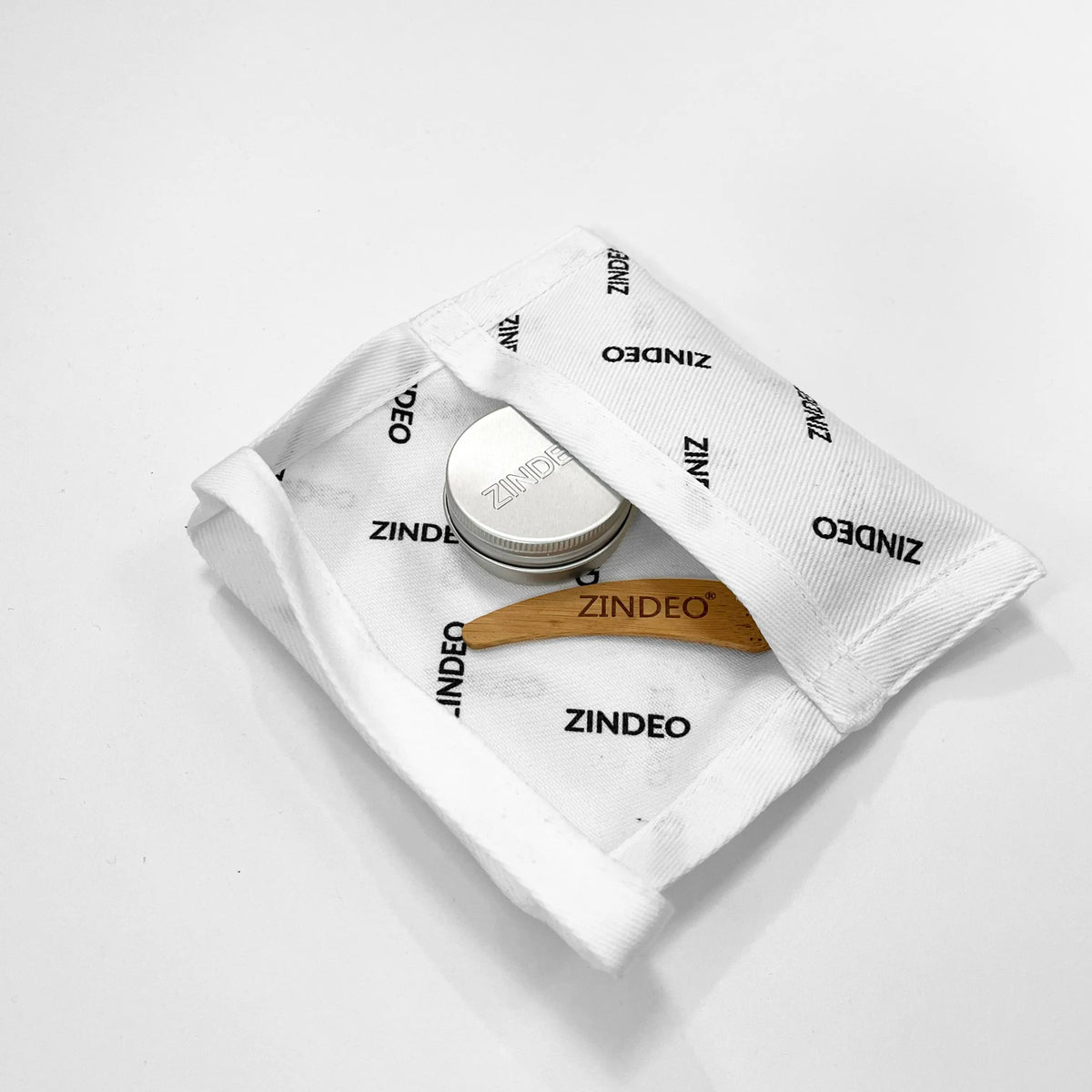 Silver ZINDEO deodorant cream tin and wooden spatula on a ZINDEO-branded cotton pouch
