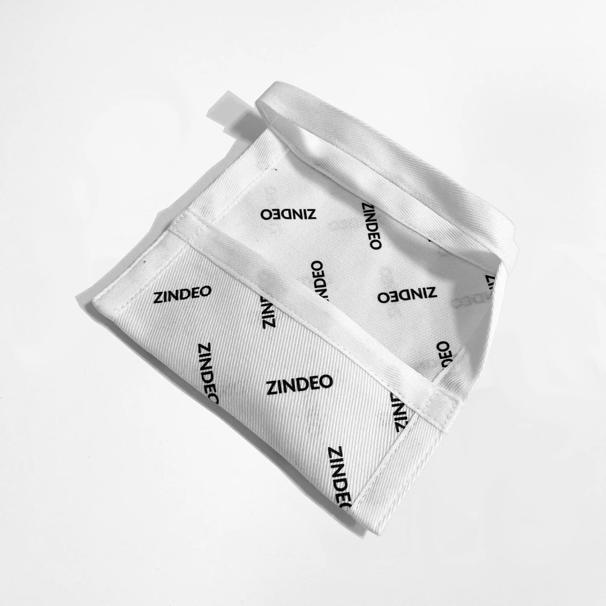 Open white cotton pouch printed all over with the ZINDEO logo on a light background