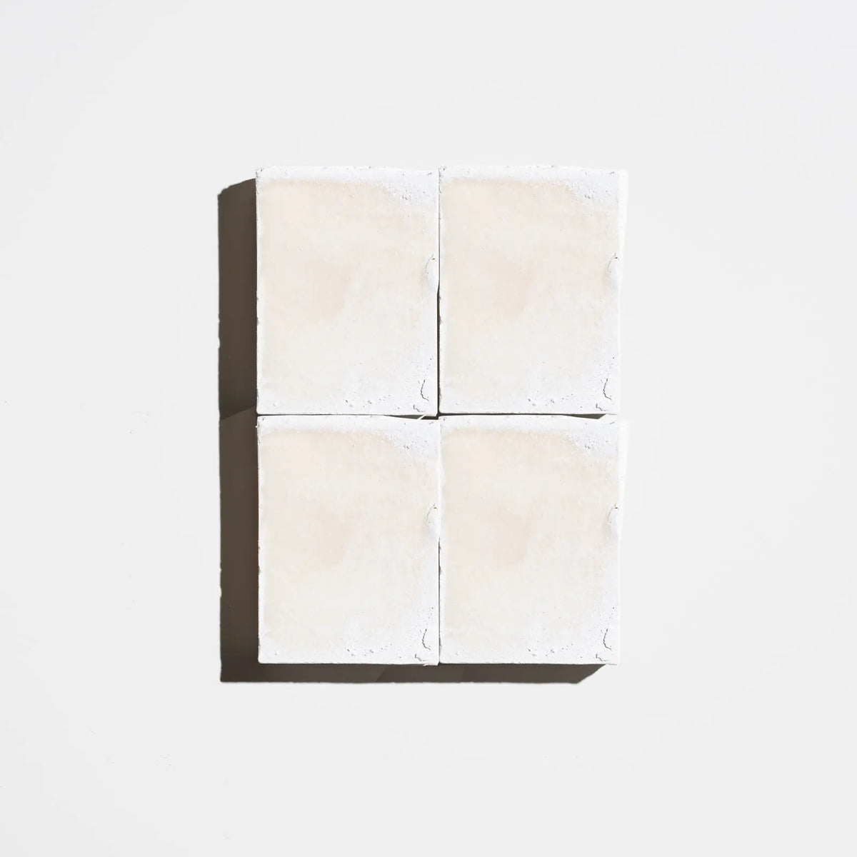 Four square cream-colored natural soap bars arranged in a 2x2 grid on a light background