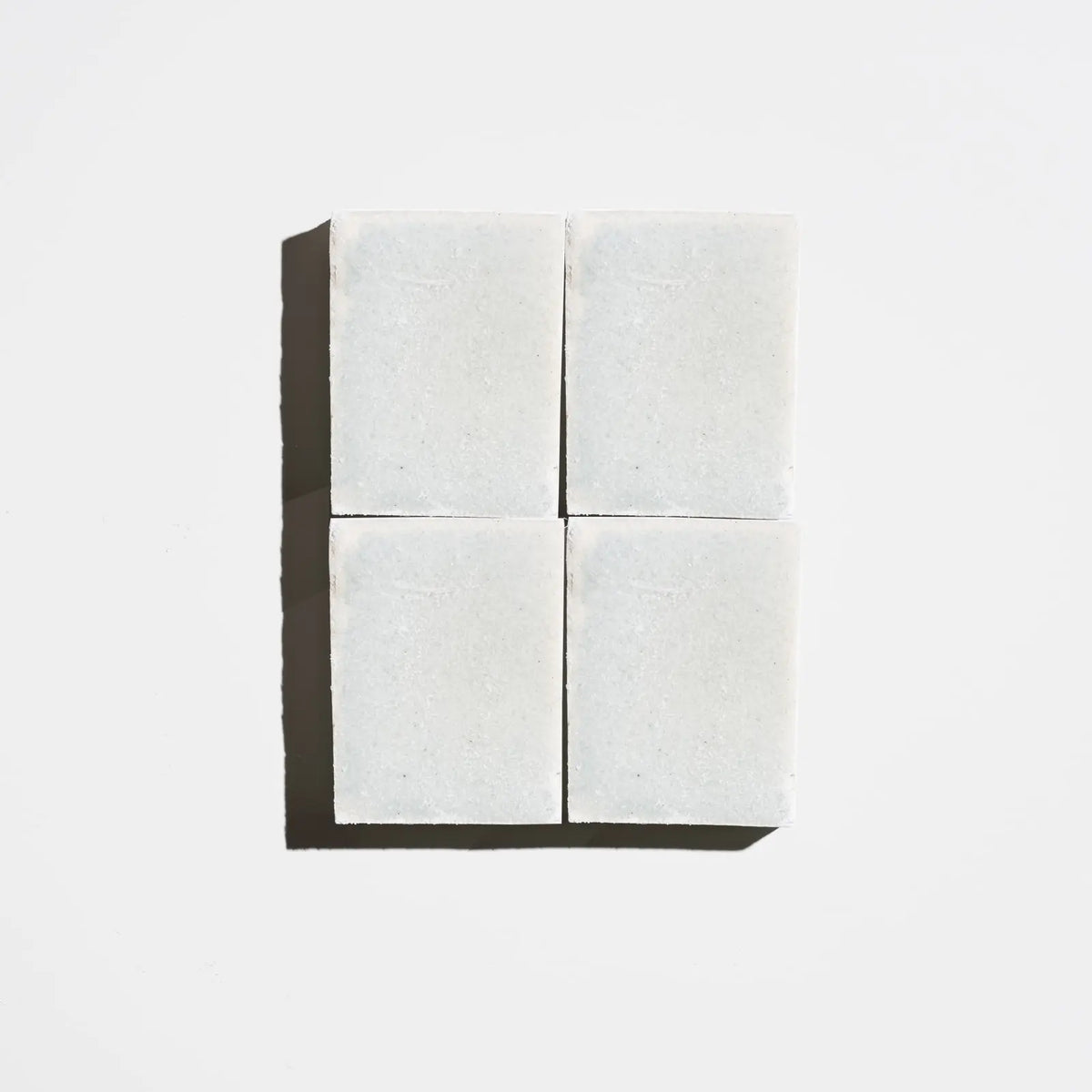 Four square pale green tea tree natural soap bars arranged in a 2x2 grid on a light background